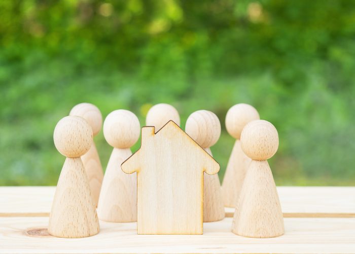 Family concept. Wooden house and many little men on a wooden table. Property division. Copy space Family concept. Wooden house and many little men on a wooden table. Property division. Copy space